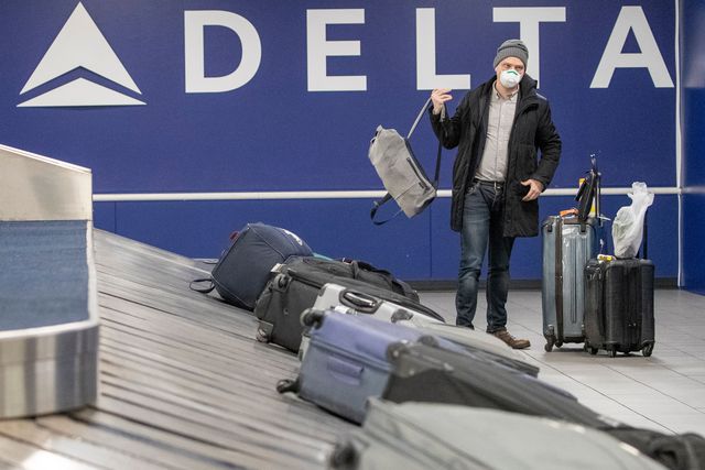 Passenger wearing a face mask collects his luggage at LaGuardia Airport, in New York.